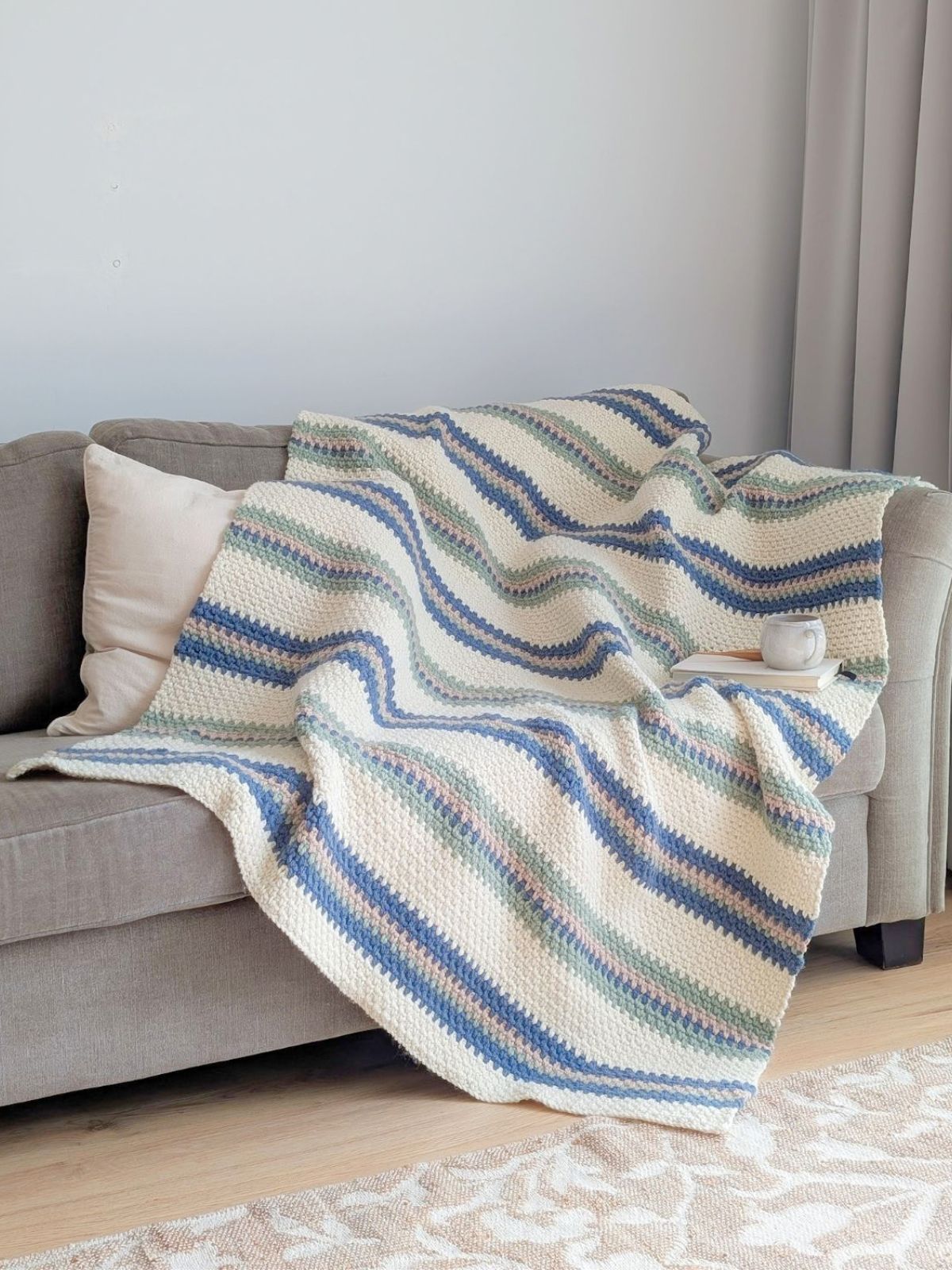 A chunky large striped crochet blanket on a couch.