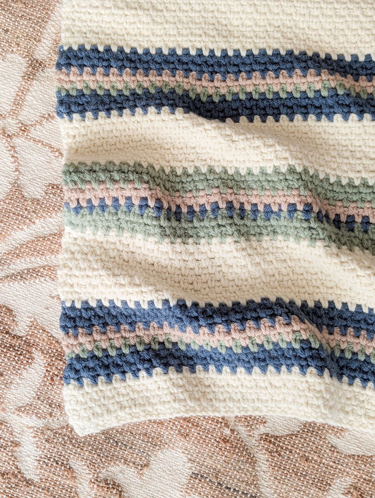 A striped crochet blanket pattern on the floor.